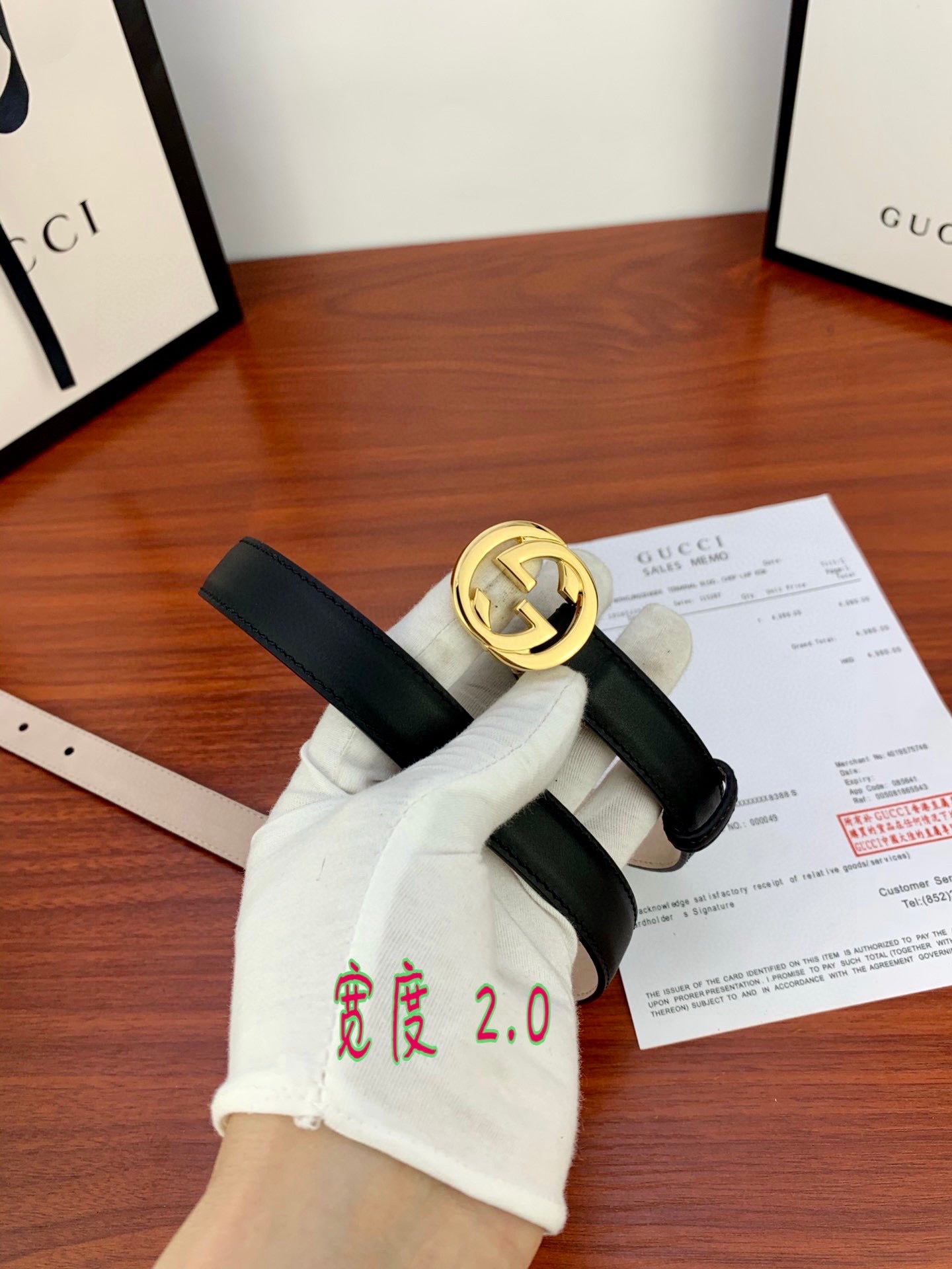 Gucci belt with dark leather strap and gold interlocking G buckle, shown flat