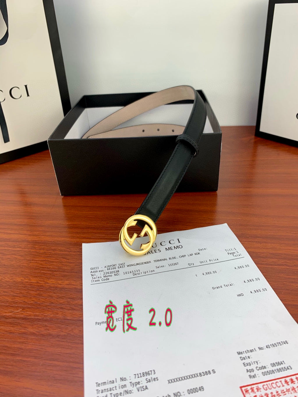 Gucci belt with dark leather strap, gold interlocking G buckle, product tag visible
