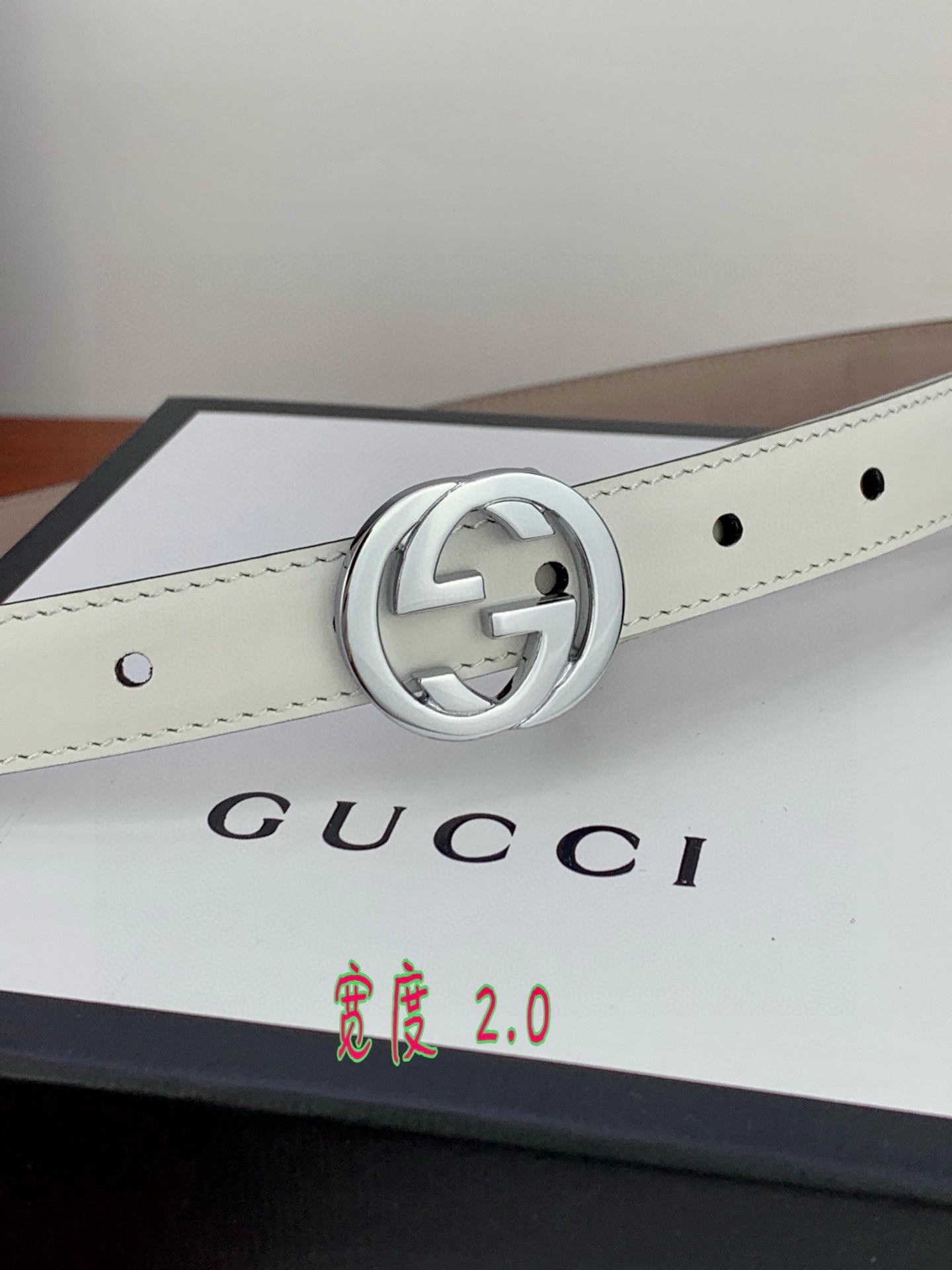 White leather belt with silver double-G buckle centered on the strap.