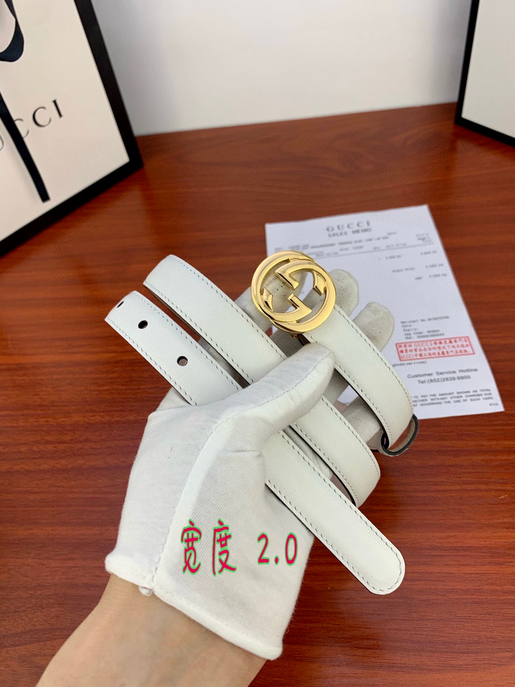 White leather Gucci belt with gold double-G buckle; strap with punched holes.