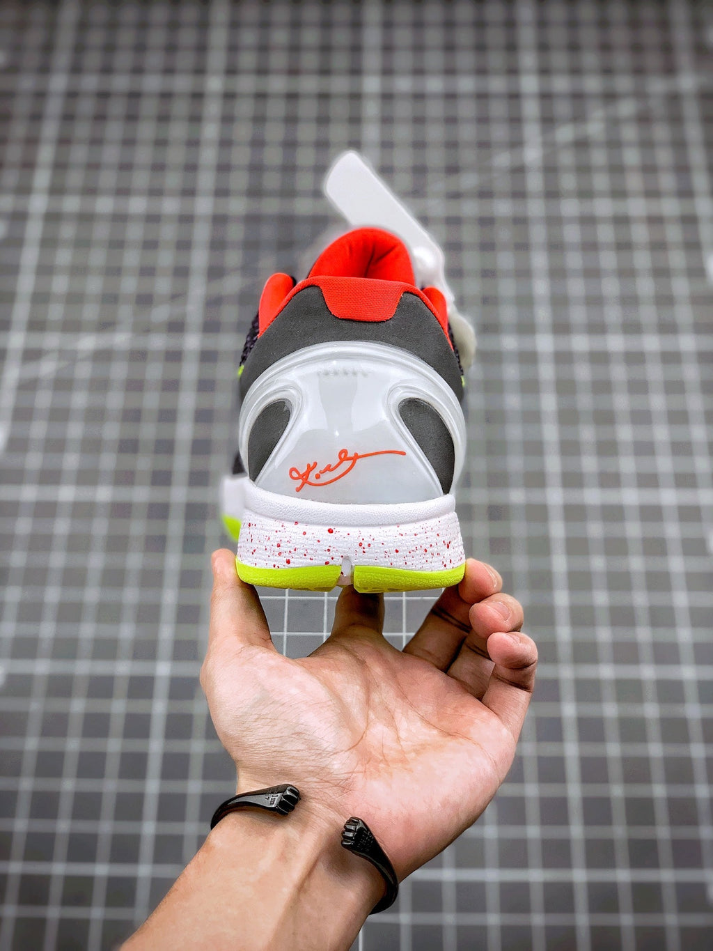 Back view of basketball sneaker with red heel collar, white upper and neon sole