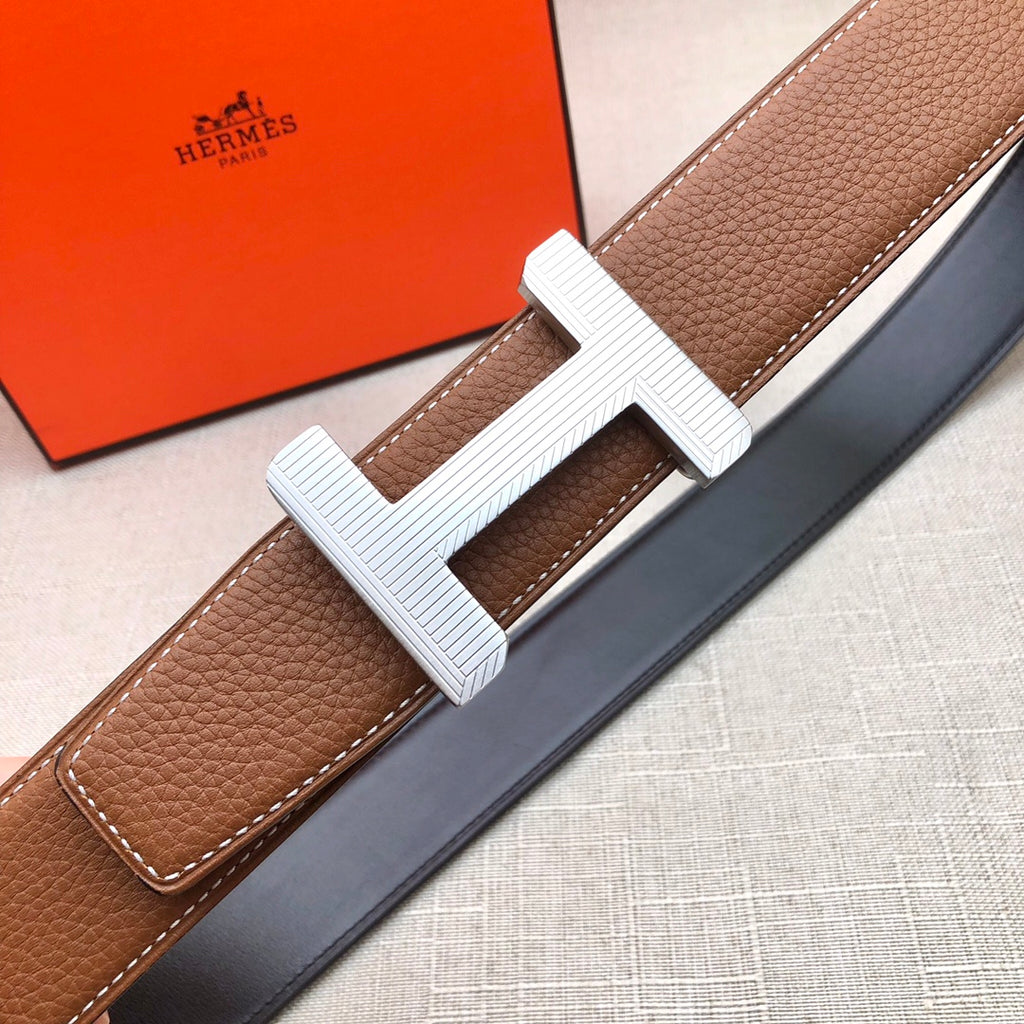 Brown leather belt with white H buckle on dark strap
