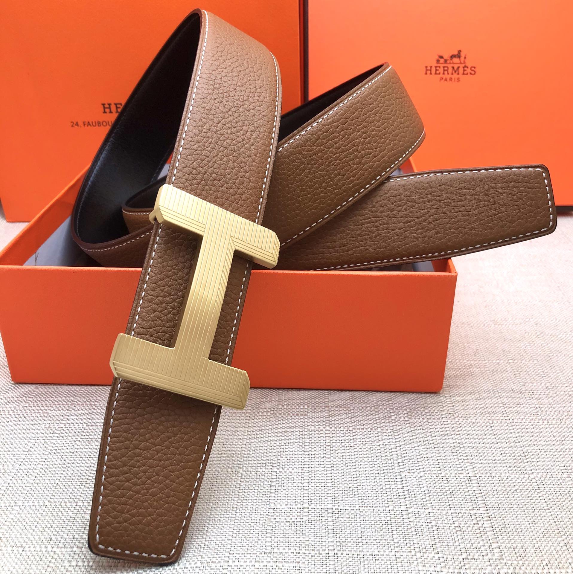 Brown leather belt with cream H-style buckle and visible strap holes