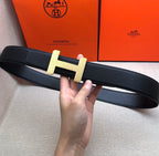 Hermes belt in dark leather with gold-tone H buckle, shown from side angle