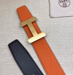 Hermes belt flat lay: orange leather strap with silver H buckle and black strap