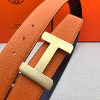 Hermes belt close-up: orange leather strap with silver H buckle and button holes