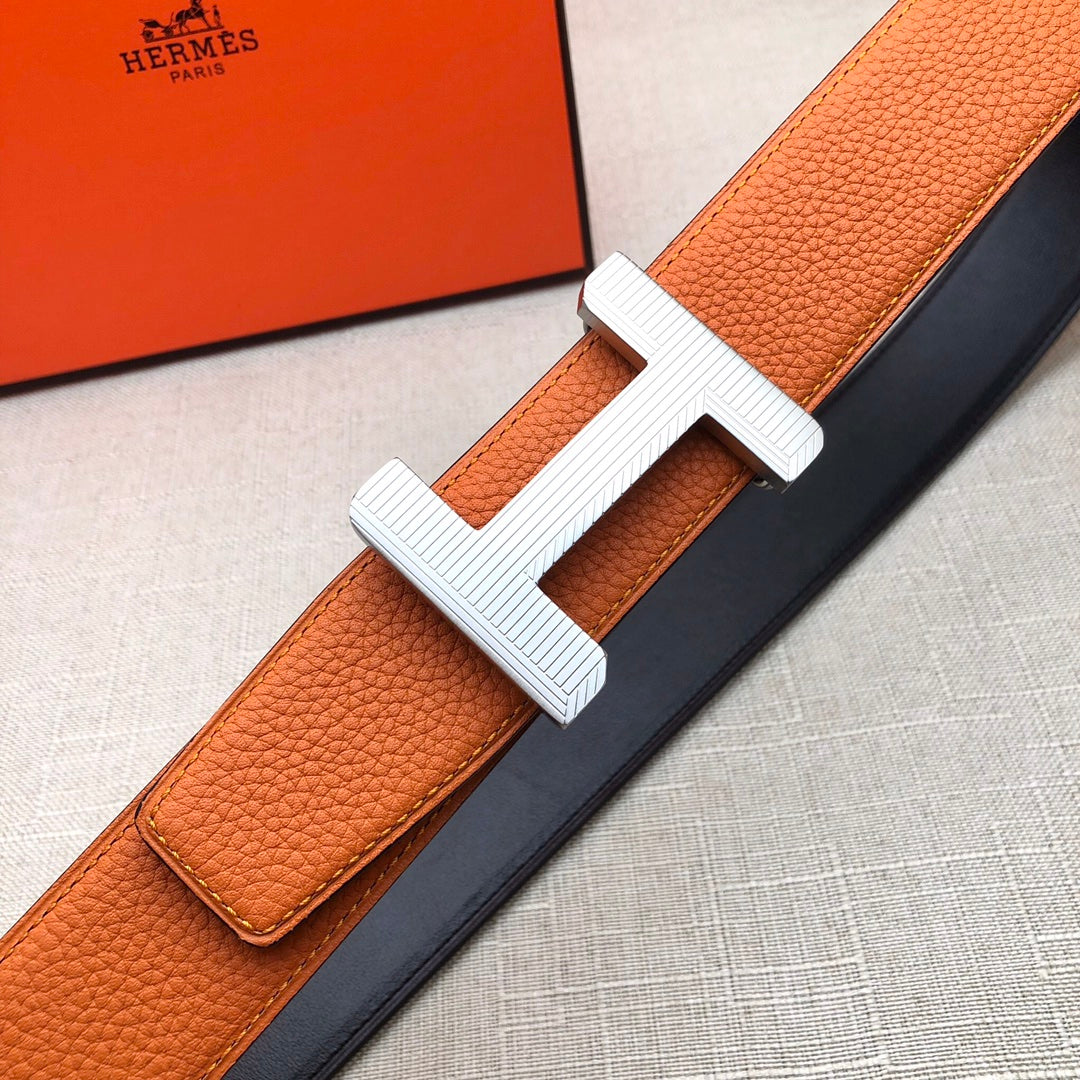 Hermes belt orange leather strap with silver H buckle on dark backing