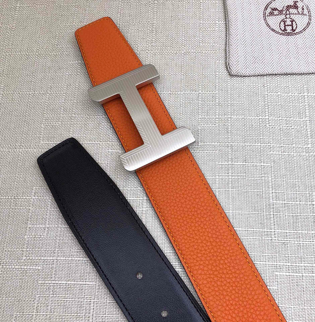Hermes belt with orange leather strap and silver H buckle, black strap with holes