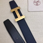 Navy leather belt with gold-tone H buckle; matching strap with two visible keeper holes.