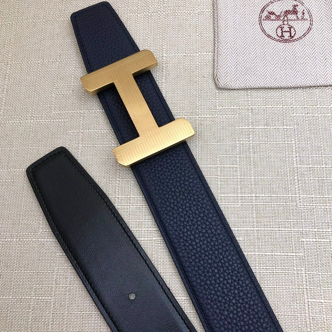 Navy leather belt with gold-tone H buckle; matching strap with two visible keeper holes.