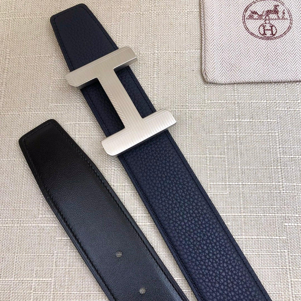 Navy leather belt with silver-tone H buckle; matching strap with two visible keeper holes.