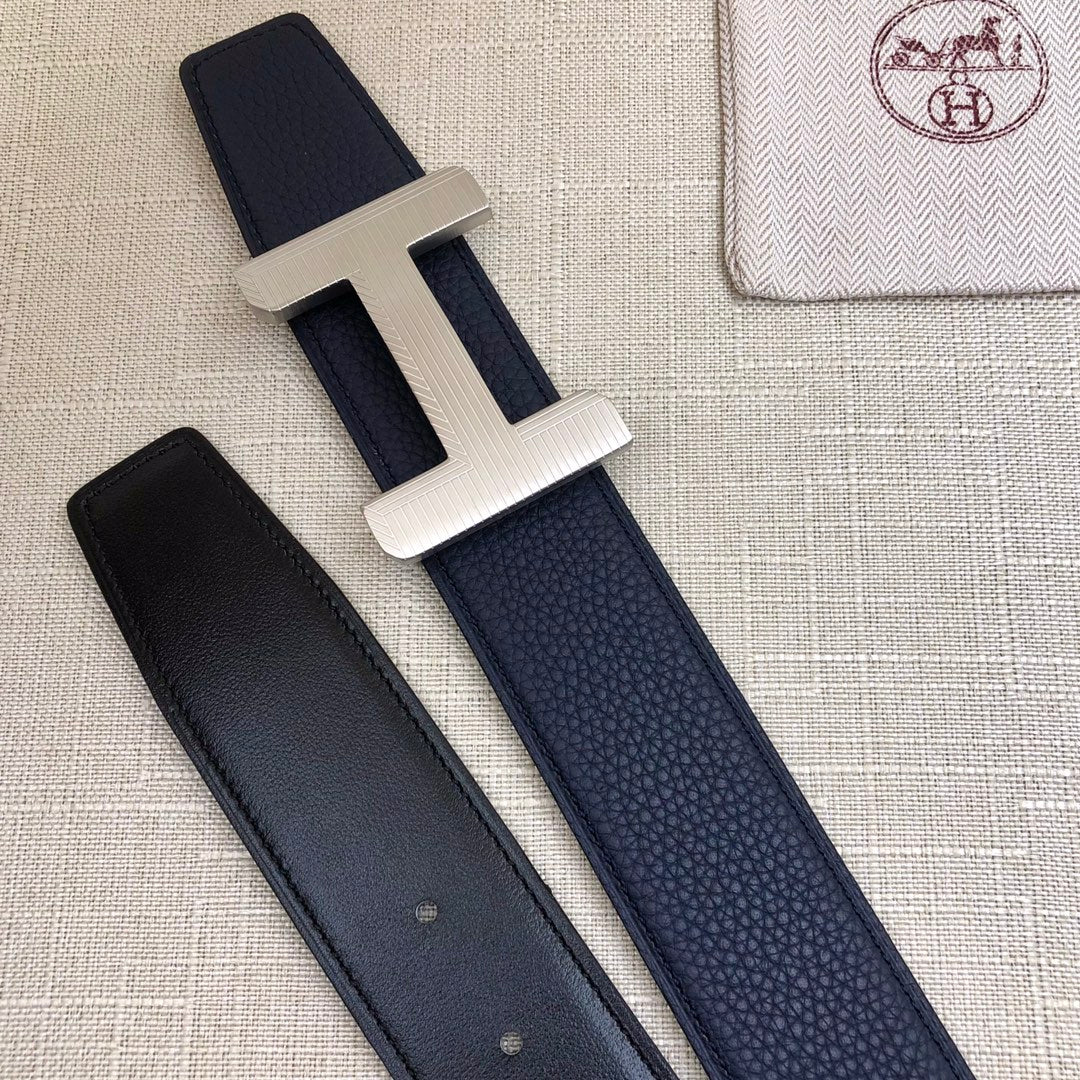 Navy leather belt with silver-tone H buckle; matching strap with two visible keeper holes.