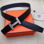 Leather belt with navy strap and silver-tone H buckle; adjustable end with keeper holes.