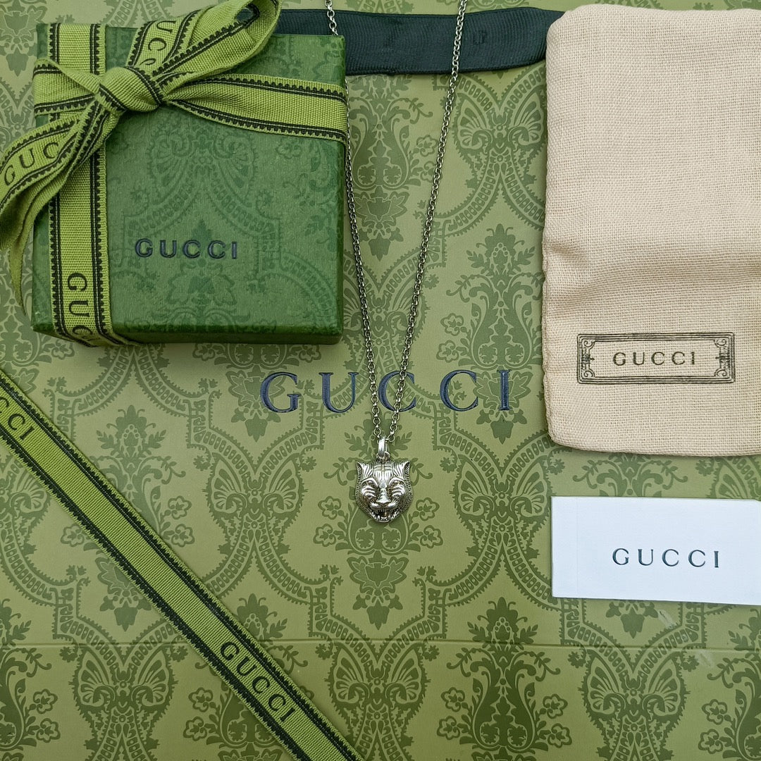 Lion head pendant on silver chain laid on patterned green pouch set