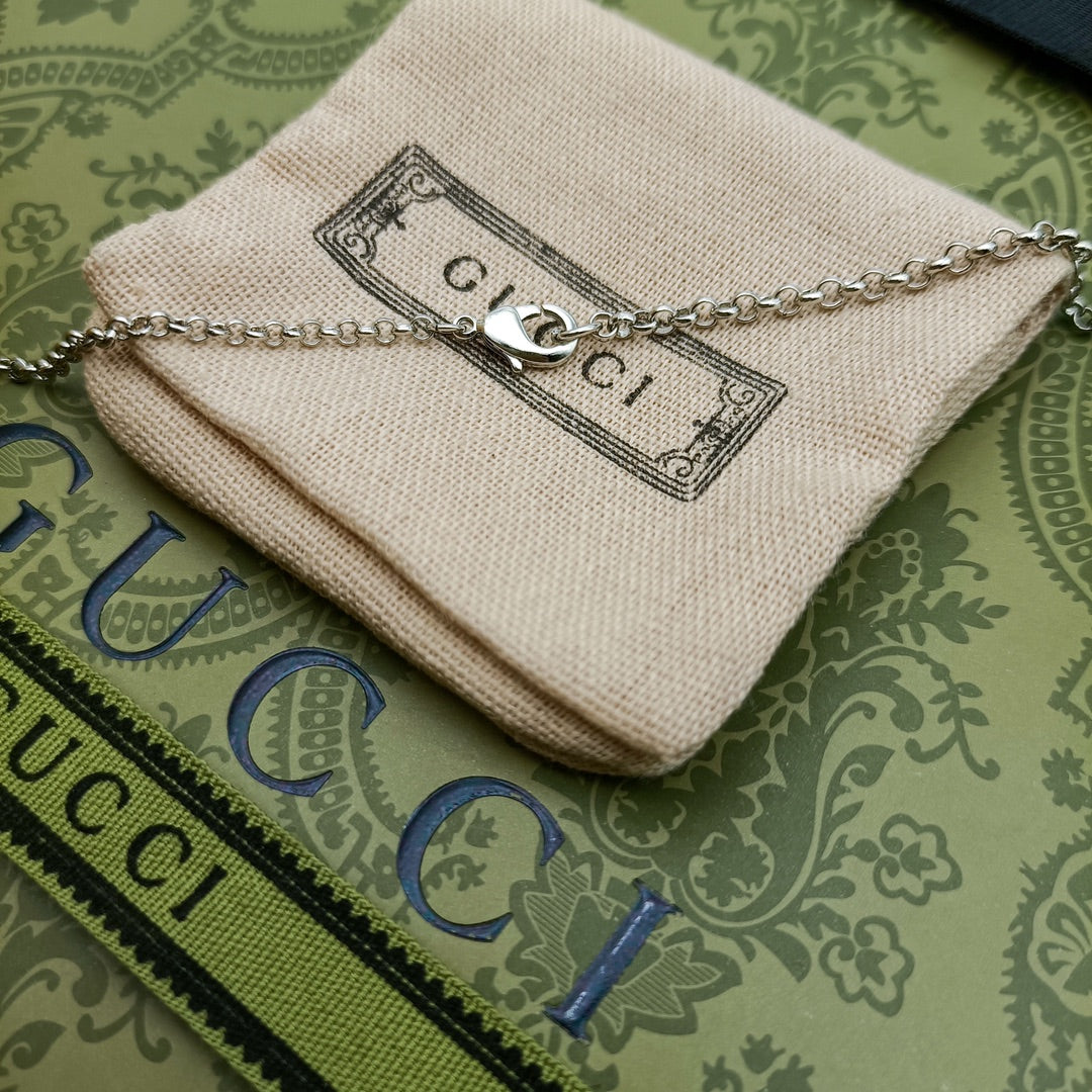Lion head pendant necklace with silver chain on cream fabric pouch