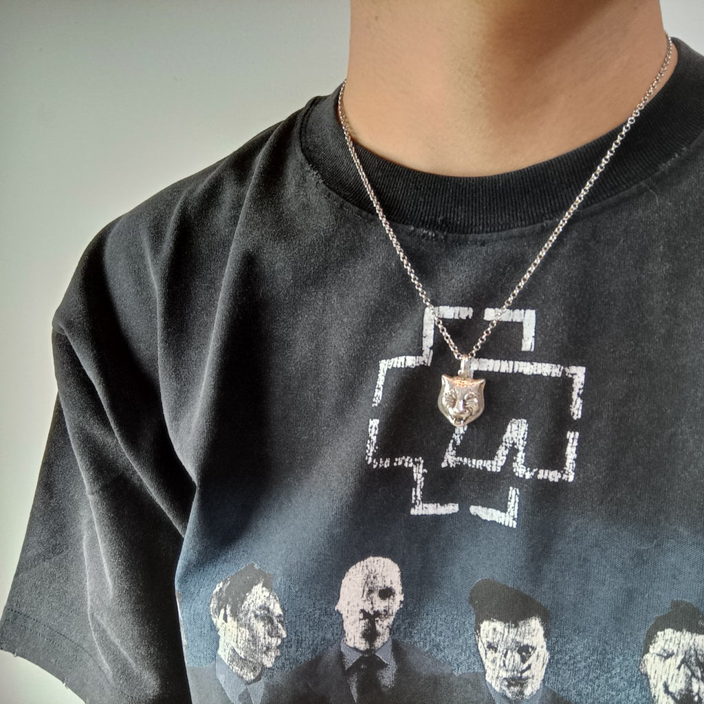 Lion head pendant necklace on silver chain worn on dark T-shirt