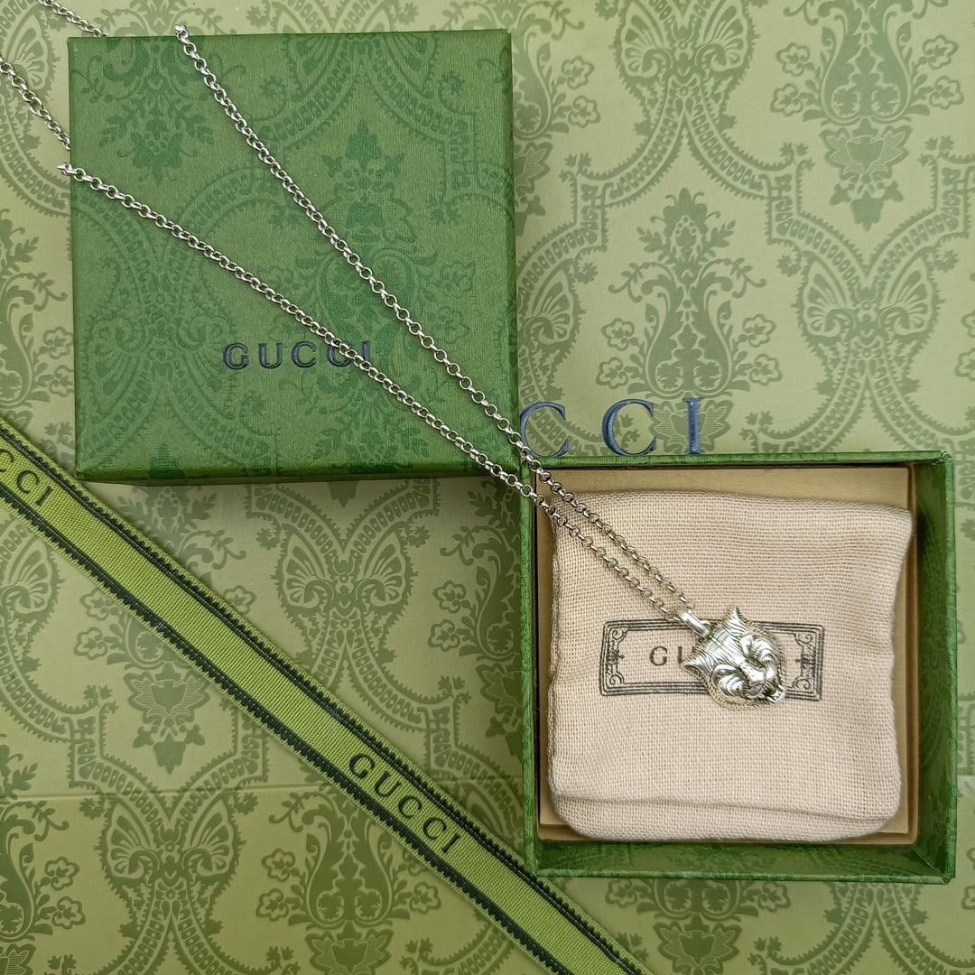 Lion head pendant necklace with silver chain resting on green gift box