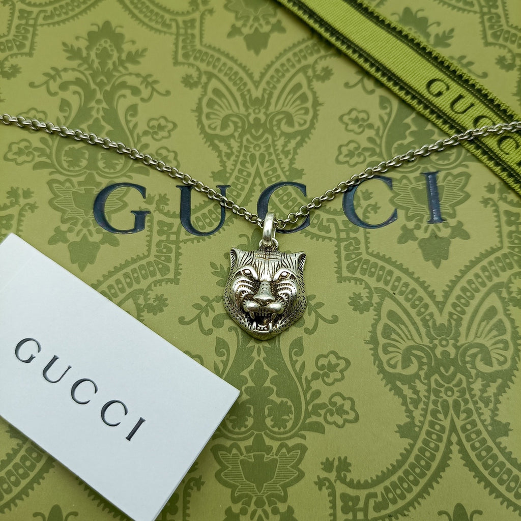 Lion head pendant necklace with silver chain on green patterned wrapping paper