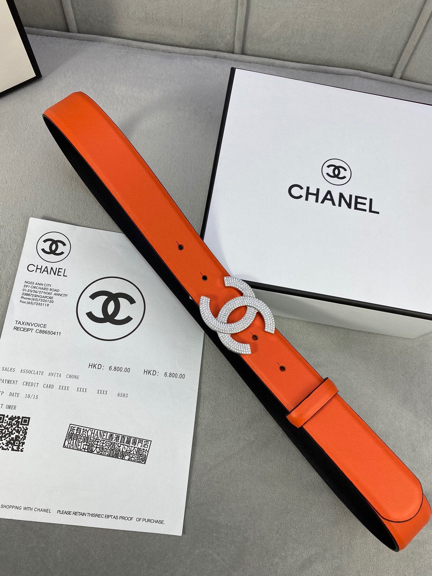 Designer belt with orange leather strap and rhinestone Chanel CC buckle, close angle