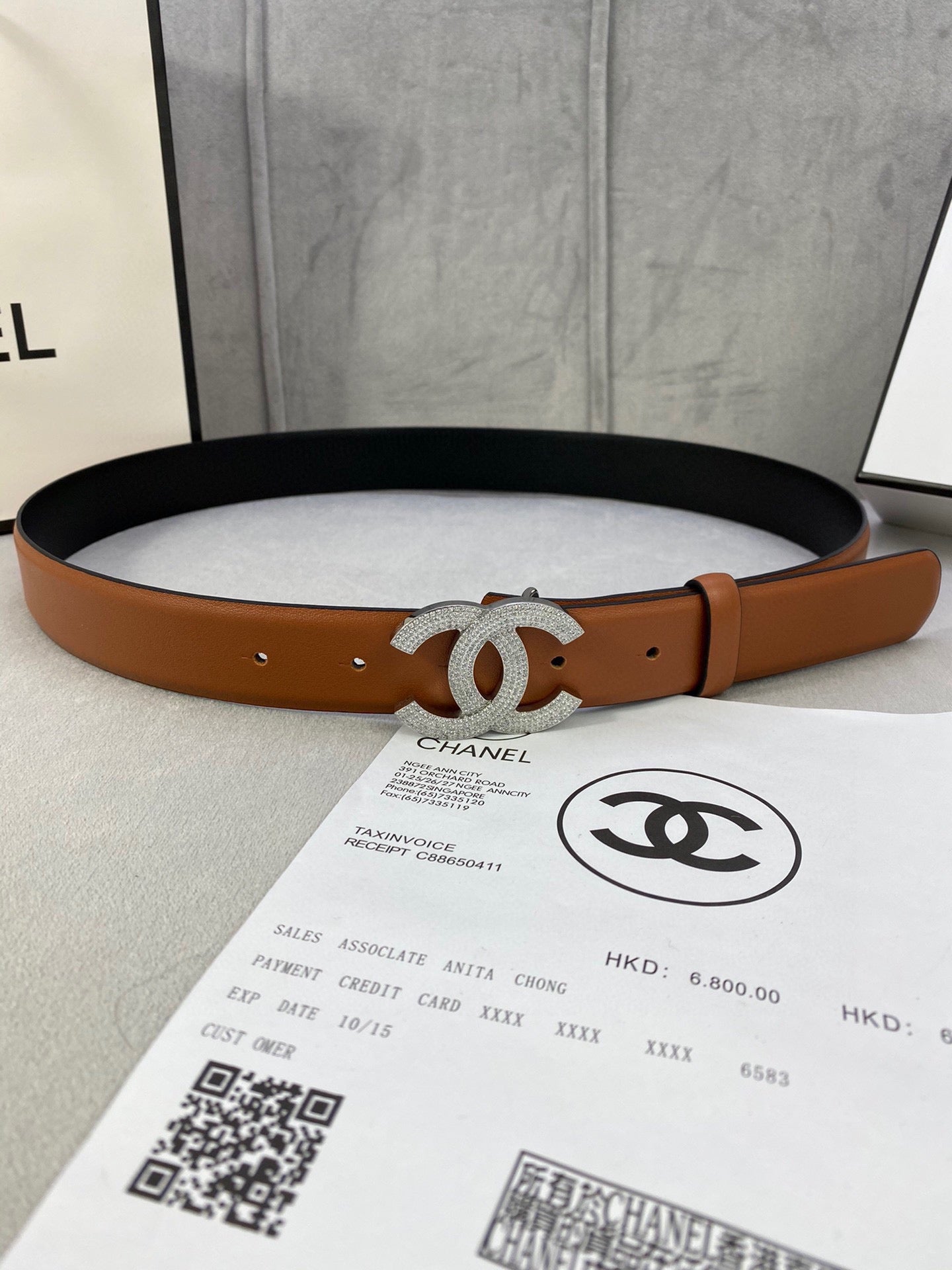 Tan leather belt with silver-tone rhinestone CC buckle, adjustable holes.