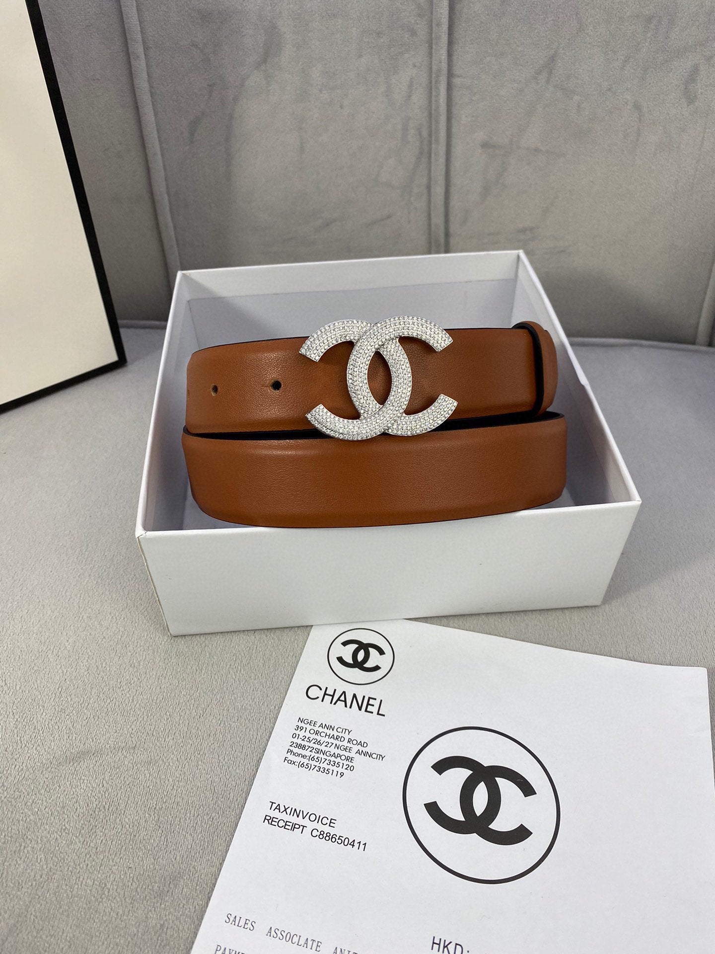 Tan leather belt with rhinestone CC buckle and matching holes, in a box.