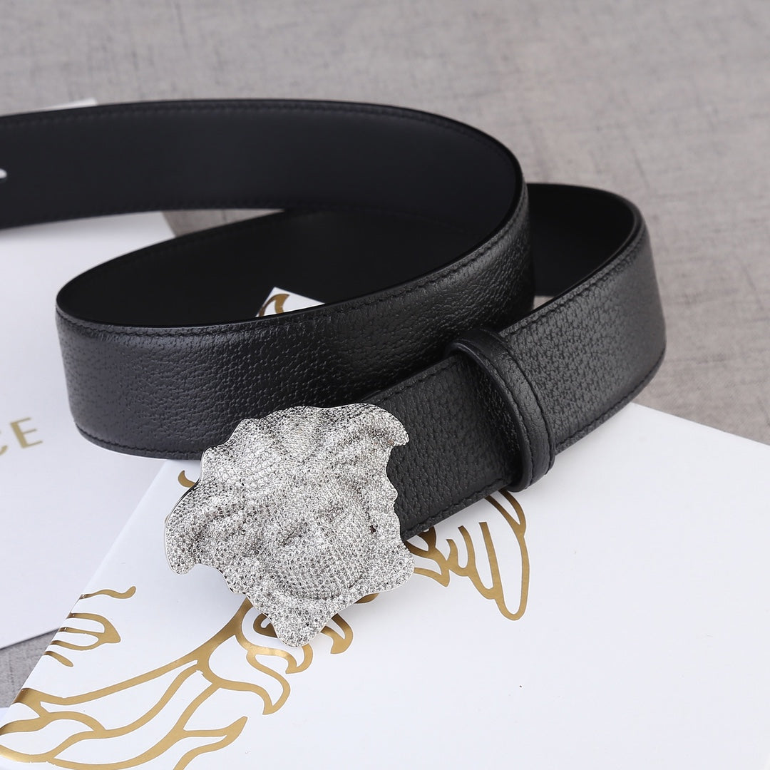 Black leather belt with gold-tone Medusa buckle on a coiled strap.