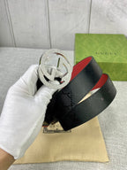 Gucci belt in hand, dark monogram strap with silver double-G buckle