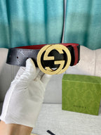Gucci belt held by hand, black monogram strap with gold buckle and red lining