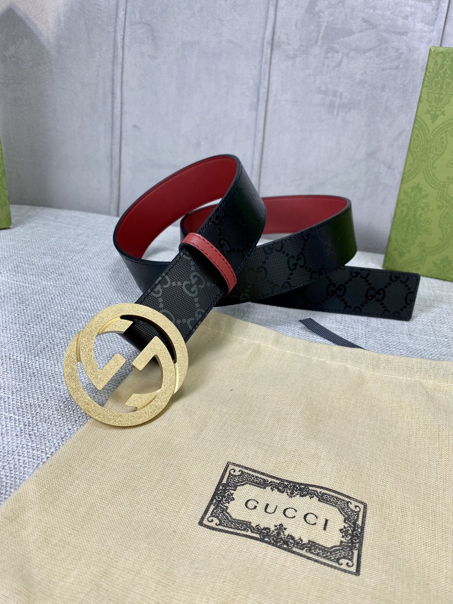 Gucci belt on display, black monogram strap with gold double-G buckle