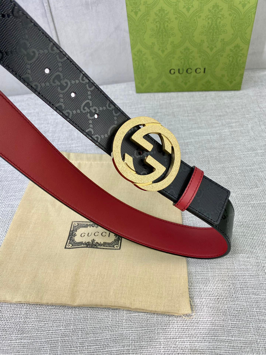 Gucci belt with black strap, red edge lining, and gold buckle close-up
