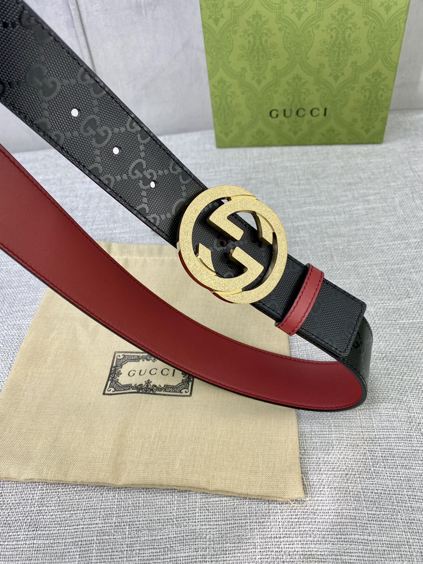 Gucci belt with black strap, red edge lining, and gold buckle close-up