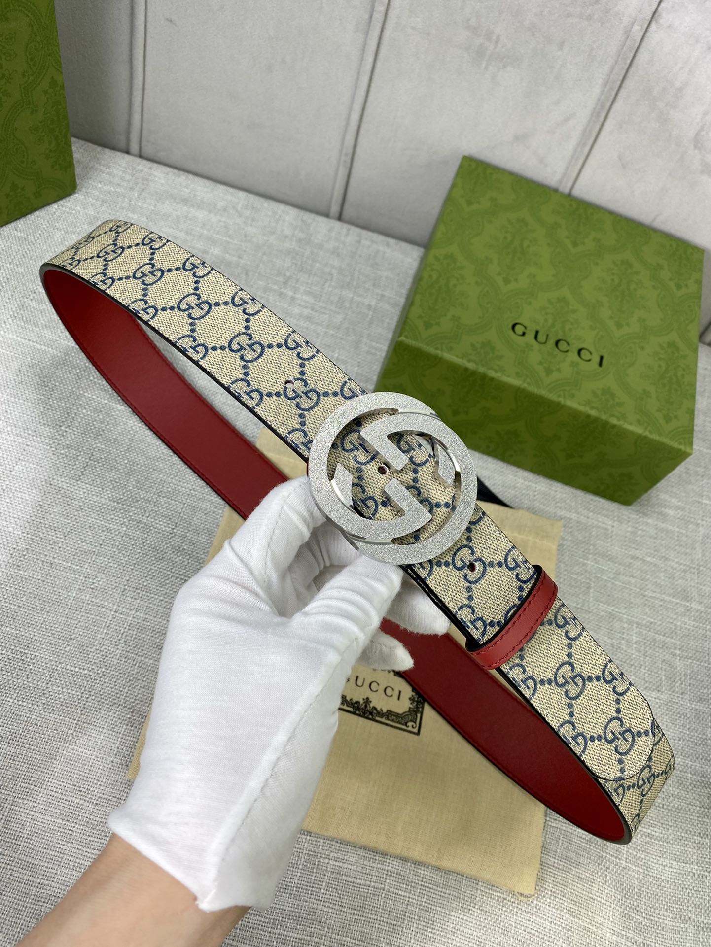 GG canvas belt with red leather edge and gold-toned interlocking buckle, laid flat