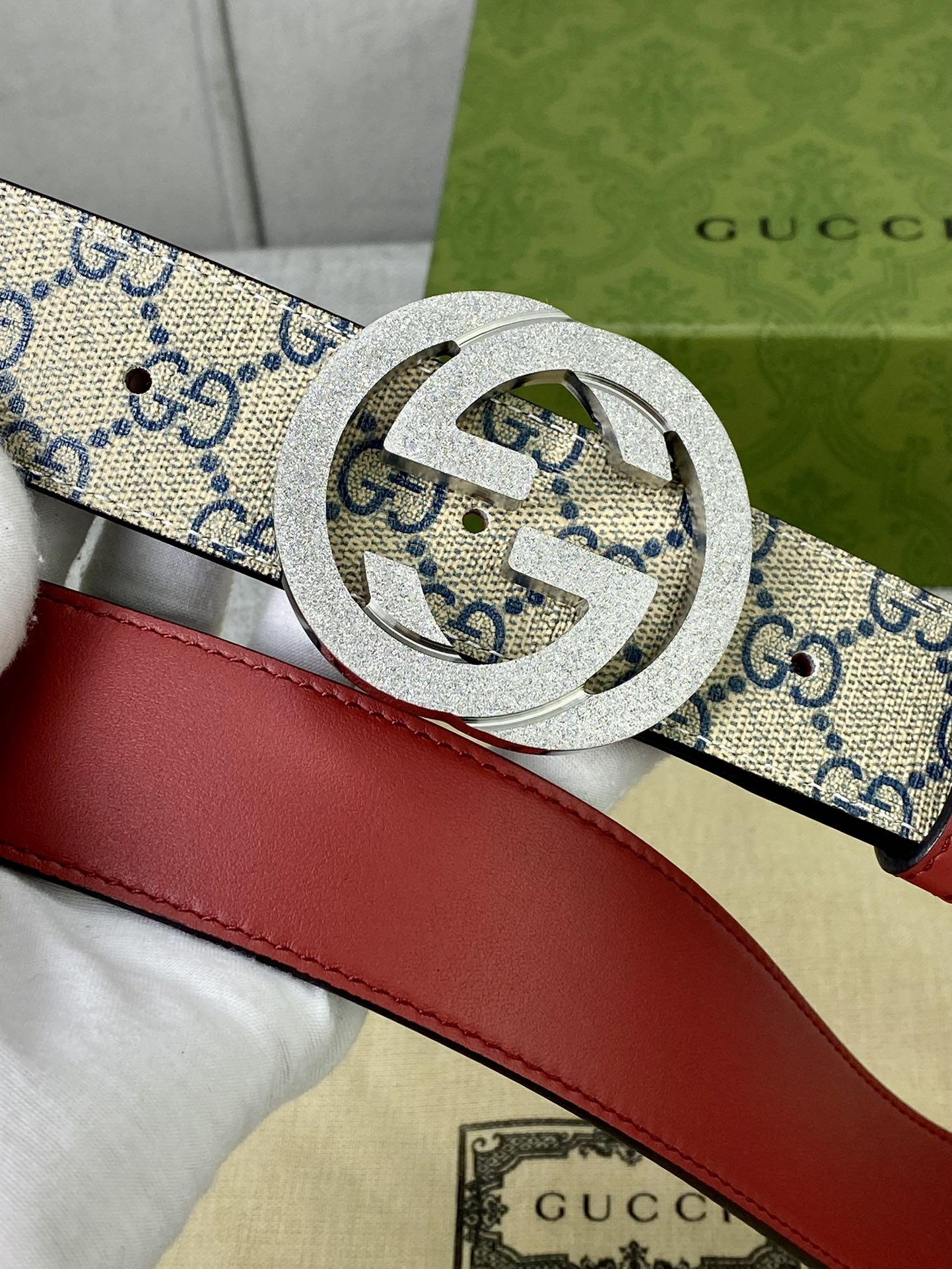 Interlocking buckle on GG canvas belt with red leather strap, close detail