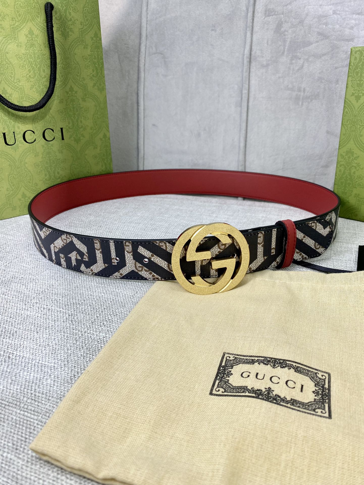 Logo-print belt with gold round G buckle, navy-and-cream strap, red leather back.