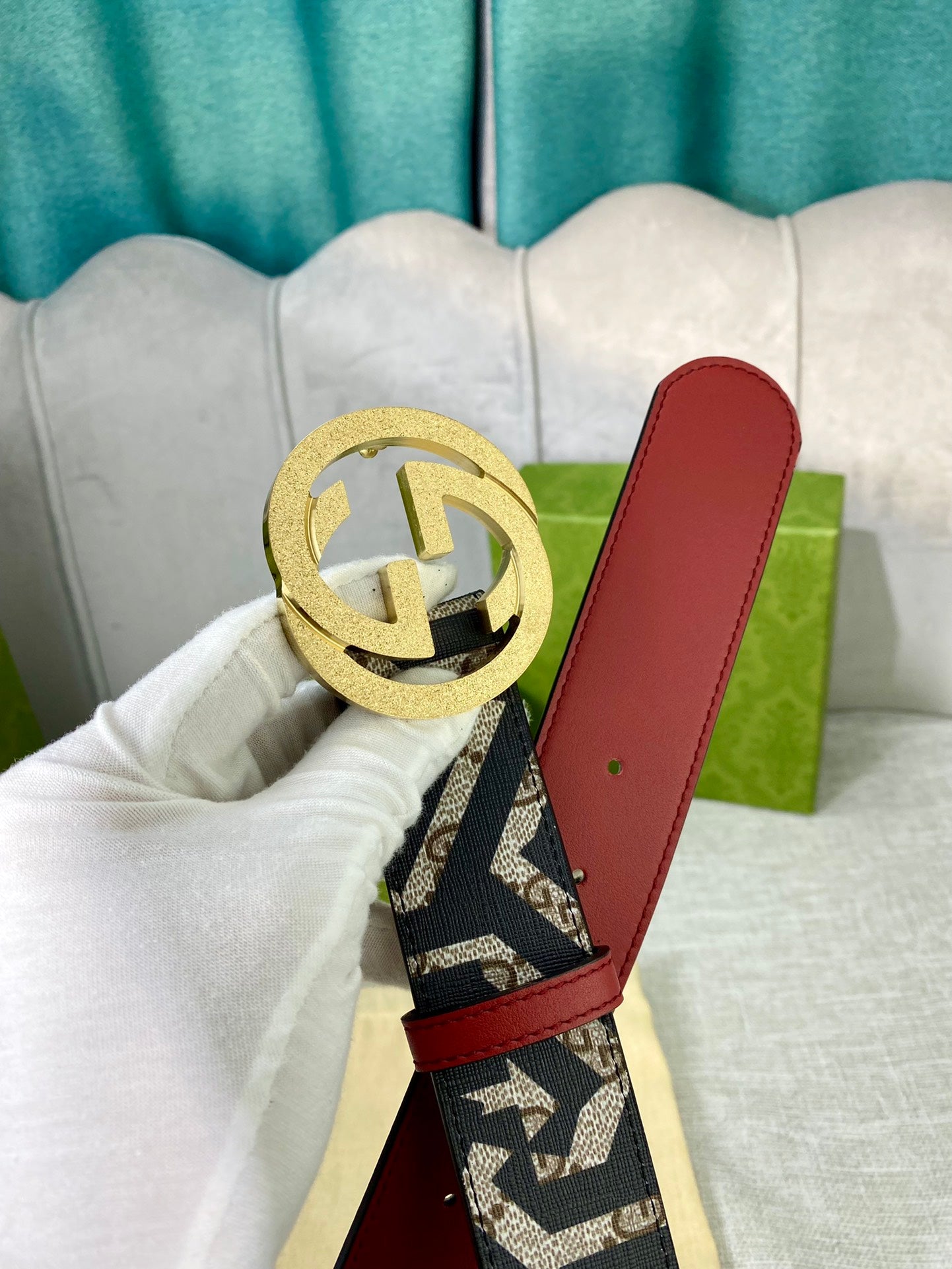 Logo-print belt with gold buckle, red leather panel, black-and-cream webbing.