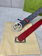 Designer belt flat on box: dark GG-print strap, red leather panel, gold-tone logo buckle.
