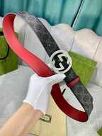 Designer belt detail with dark GG-print strap, red underside leather, and silver-tone logo buckle.