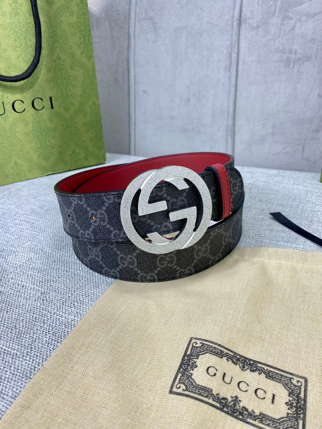 Designer belt coiled: dark GG-print canvas with red leather trim and silver-tone G buckle.