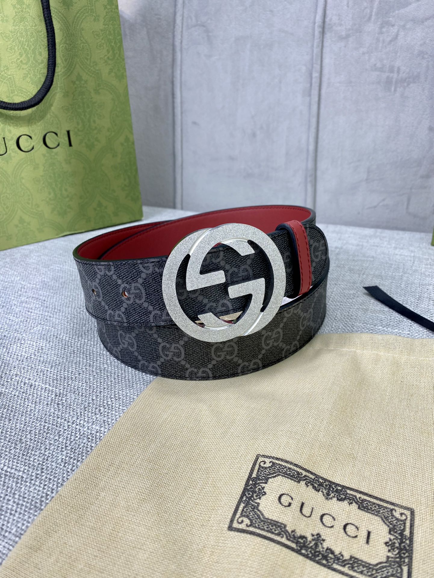 Designer belt coiled: dark GG-print canvas with red leather trim and silver-tone G buckle.