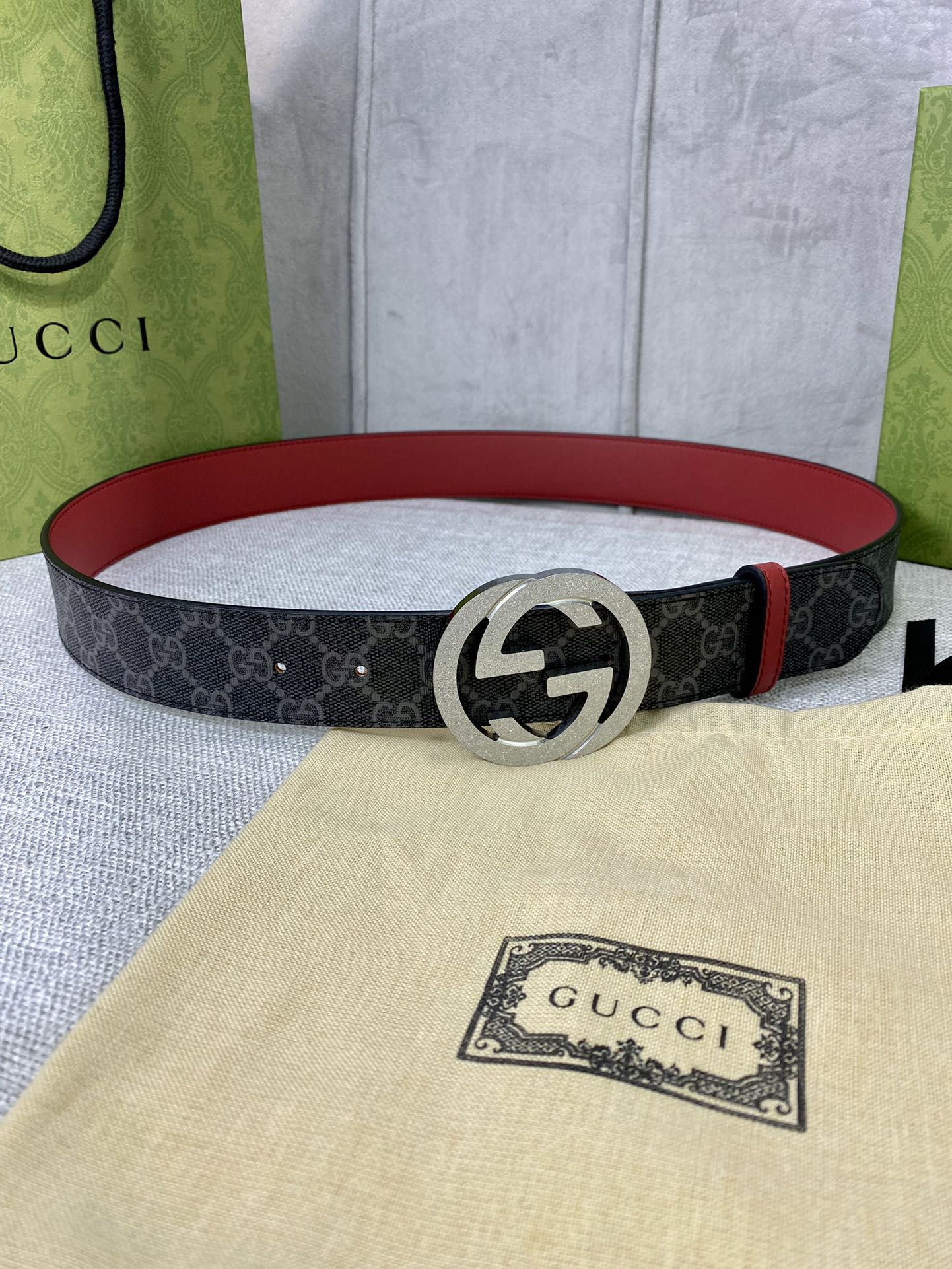 Designer belt with dark GG-print canvas and red leather edge, large silver-tone buckle.