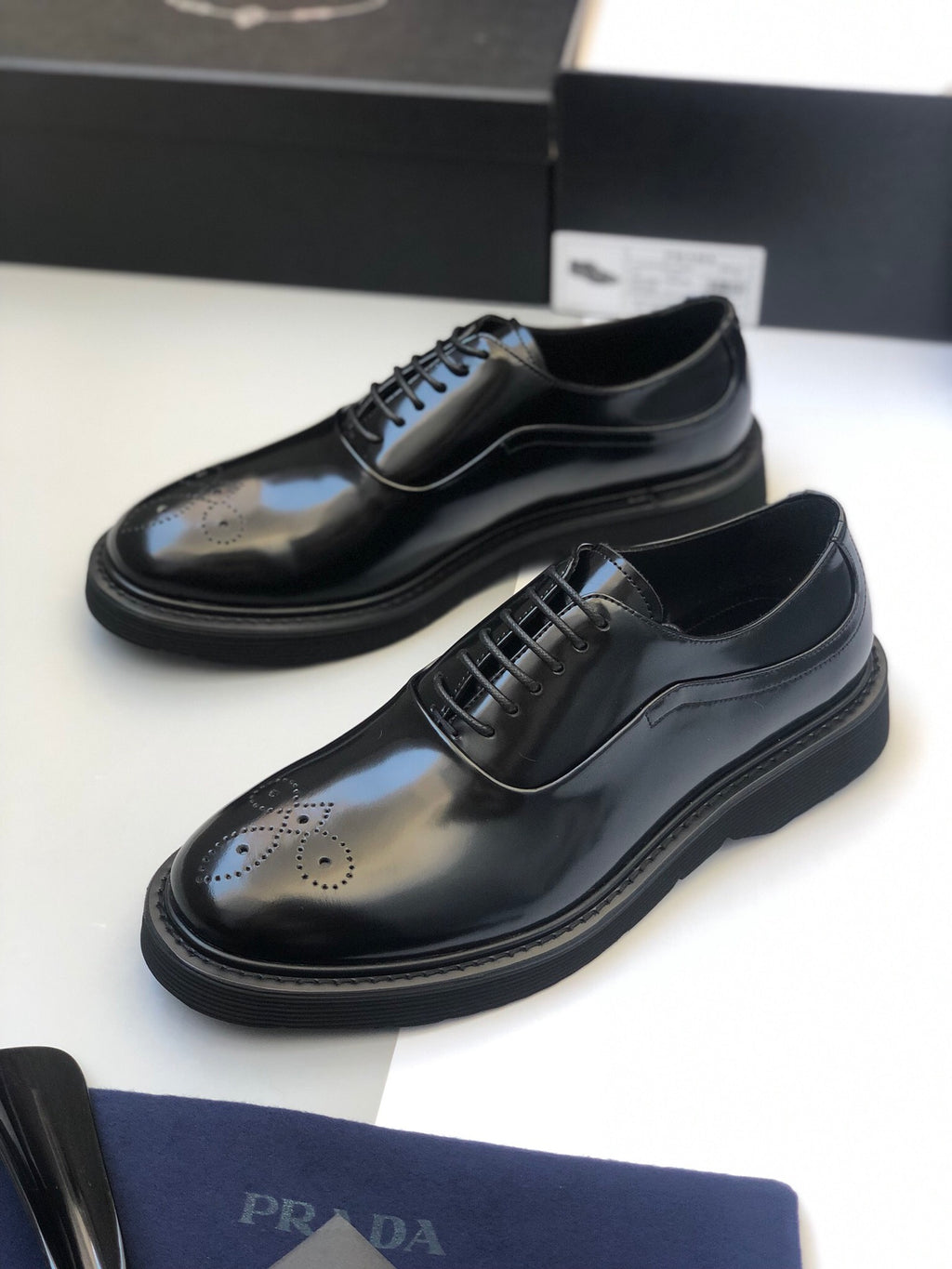 Black lace-up oxford shoes with brogue detailing and rounded toe