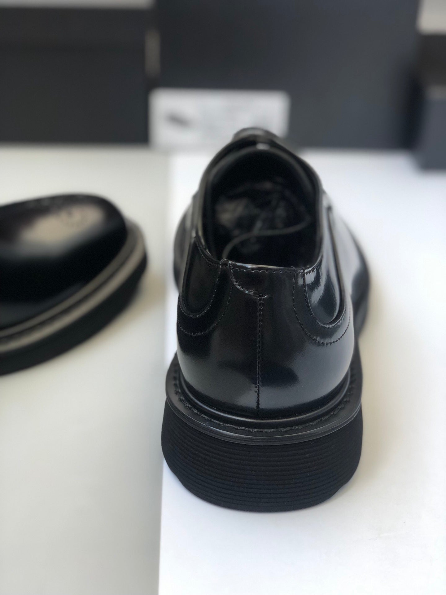 Black lace-up shoe back view with thick textured outsole