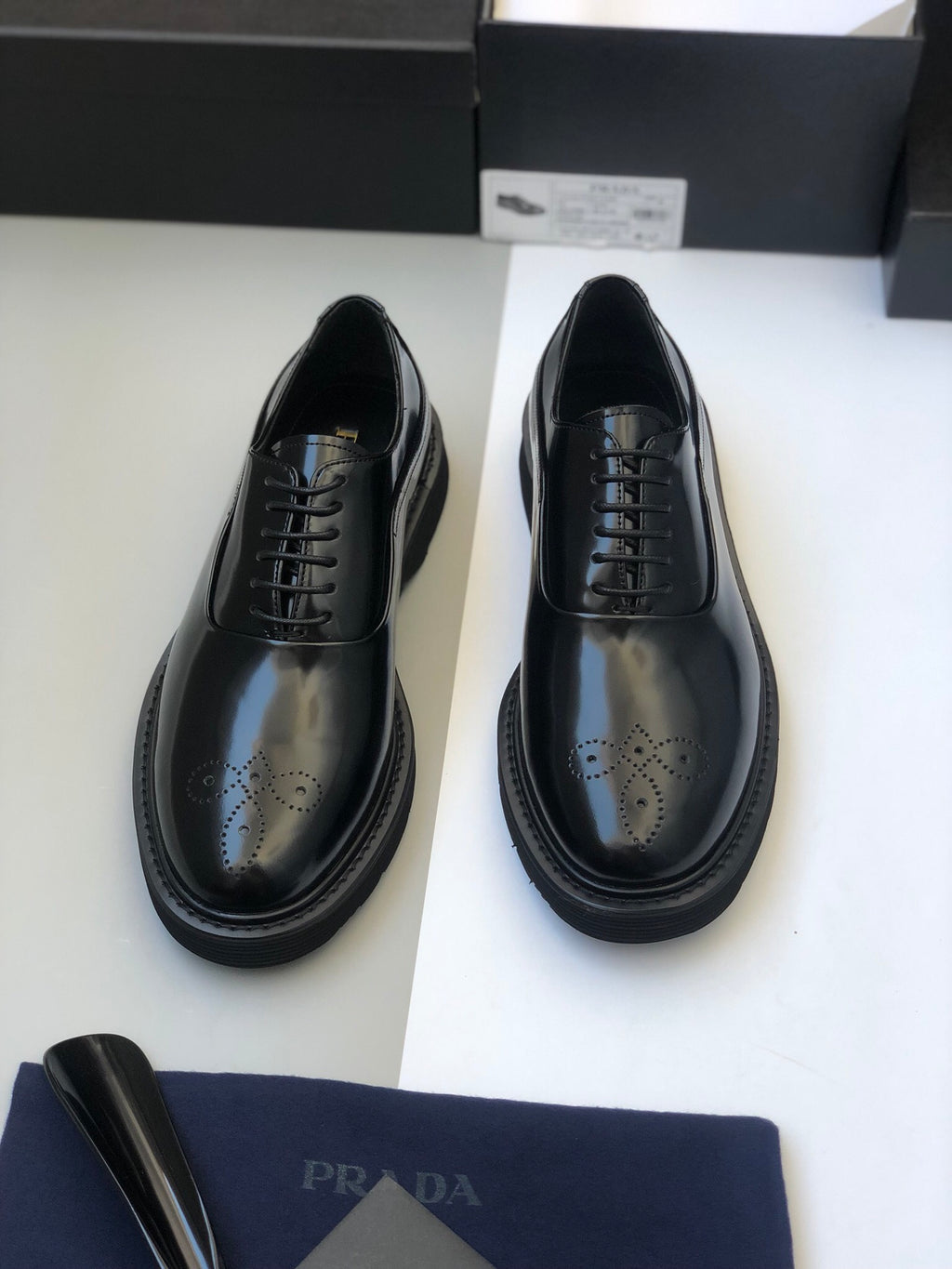 Black lace-up leather shoes with wingtip perforations and thick rubber sole