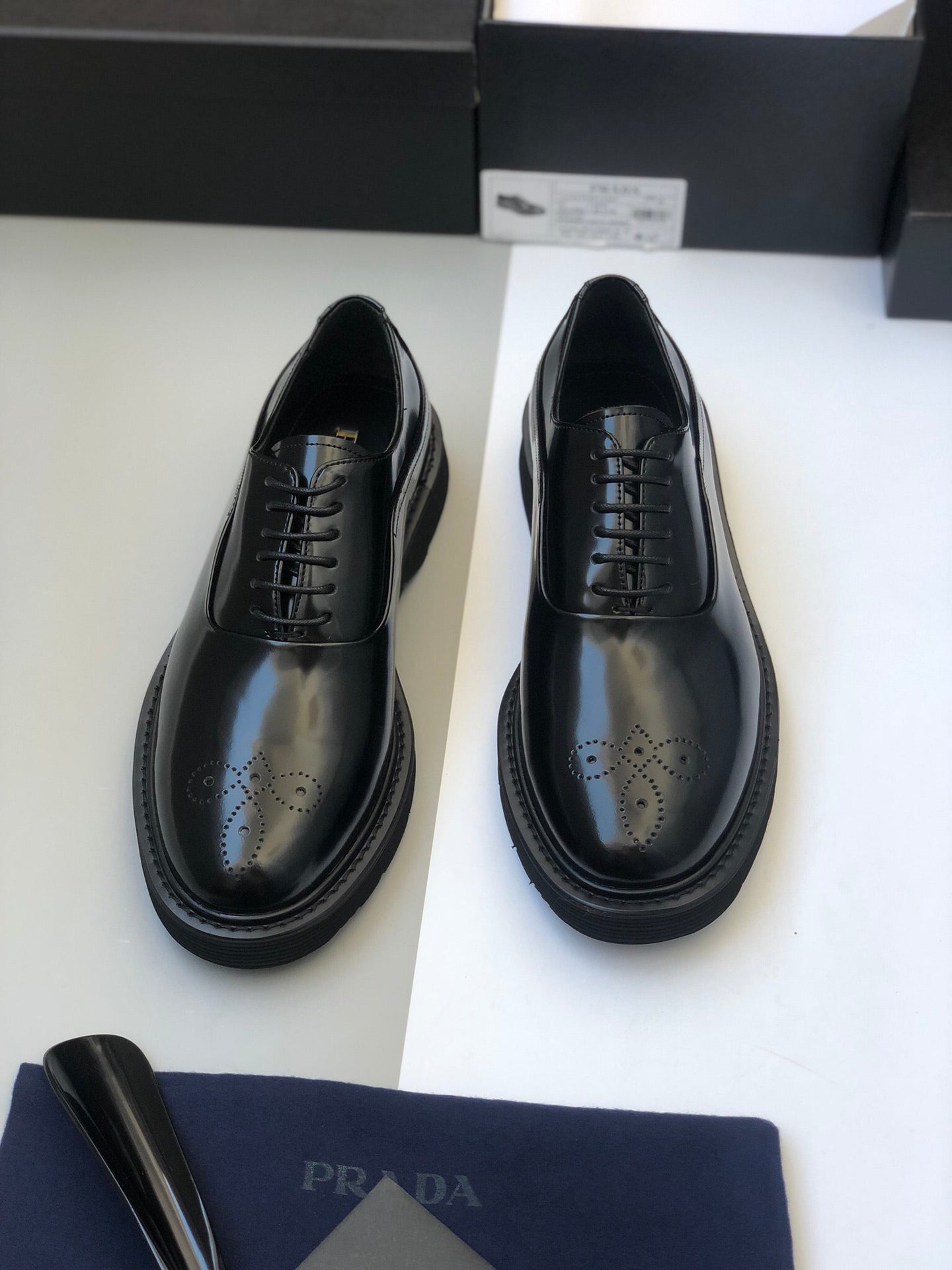 Black lace-up leather shoes with wingtip perforations and thick rubber sole