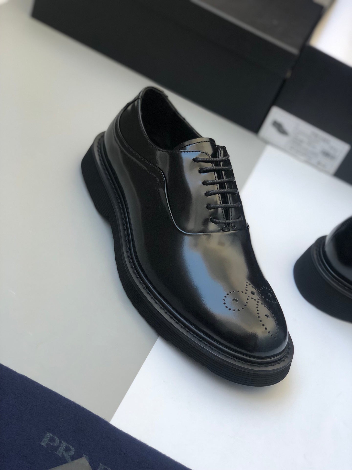 Black polished lace-up shoe with brogue perforations and low profile sole