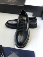 Black lace-up leather shoe with wingtip perforations and rounded toe