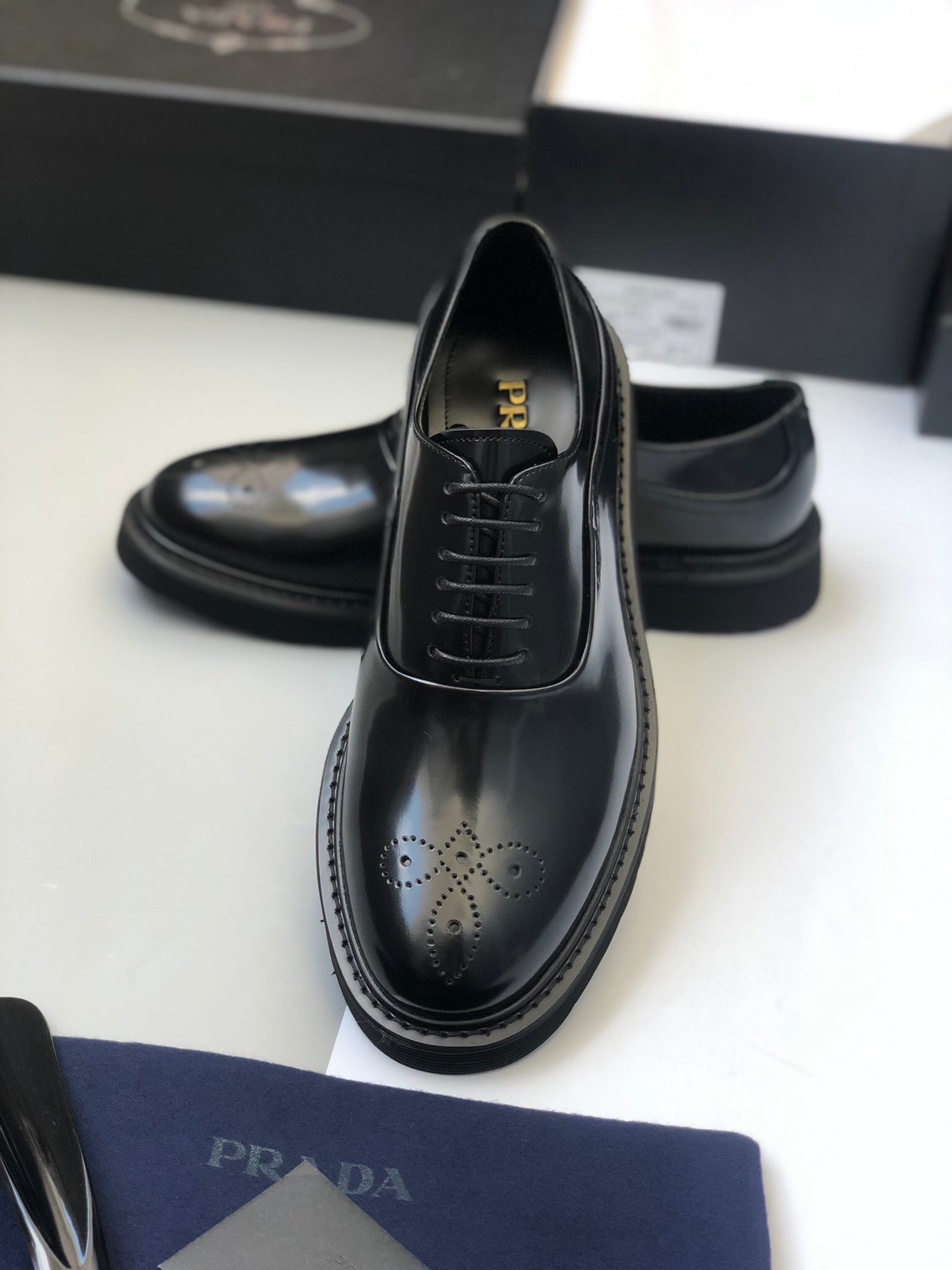 Black lace-up leather shoe with wingtip perforations and rounded toe