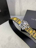 Designer belt angled view: black strap with gold medallion trim and silver lion buckle