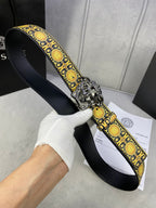 Designer belt held in hand: black strap, gold medallion trim, and silver lion buckle