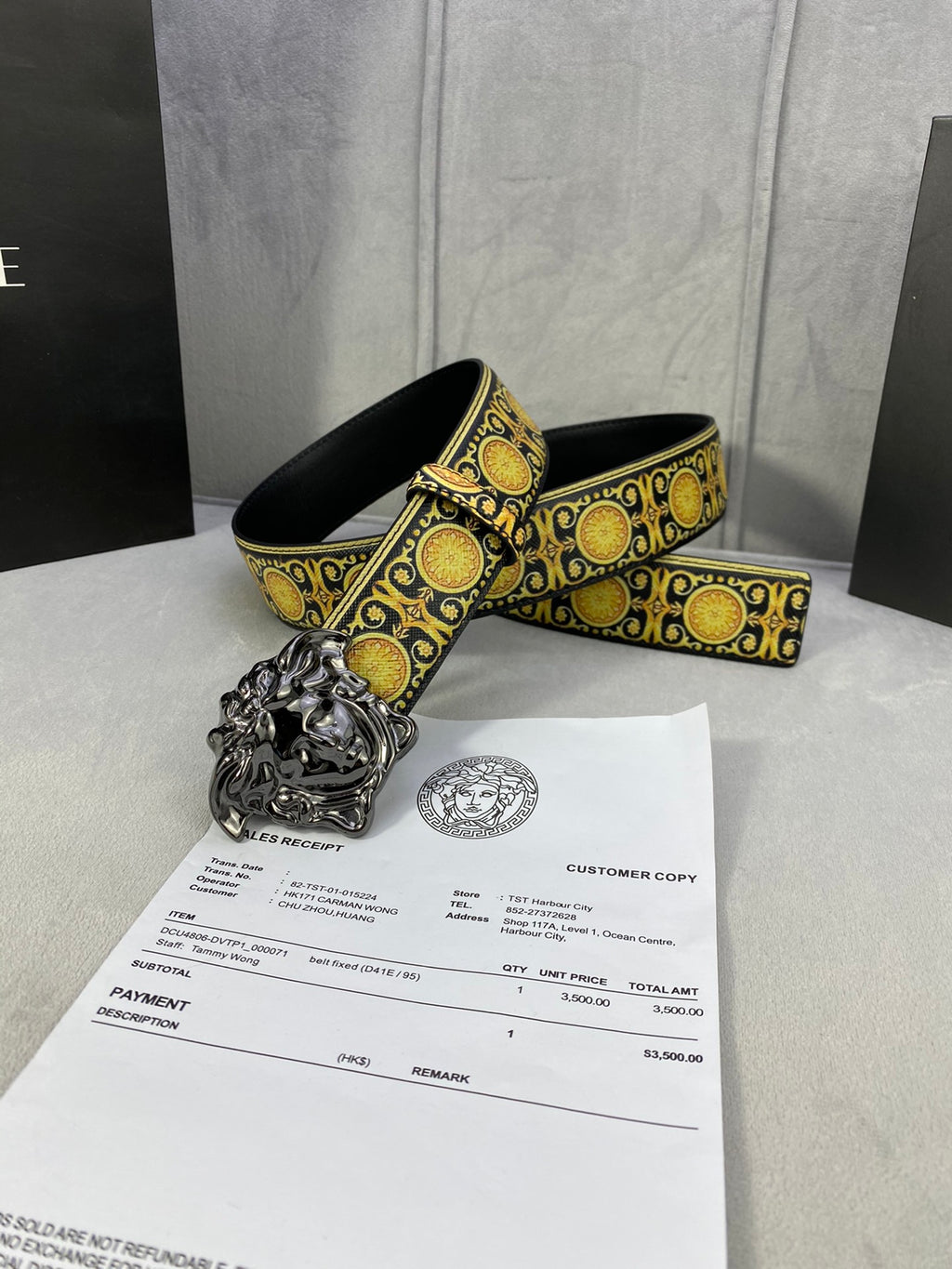 Designer belt and buckle detail: gold medallion trim on black strap with silver lion buckle